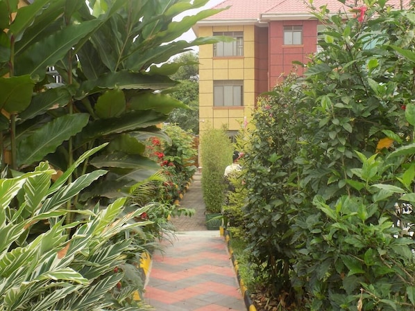 Stroll through the beautifully maintained garden, leading to a multi-story building with a vibrant facade.