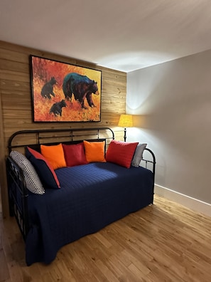 Cozy bedroom with a bed, wooden headboard, and a wall-mounted painting of bears.