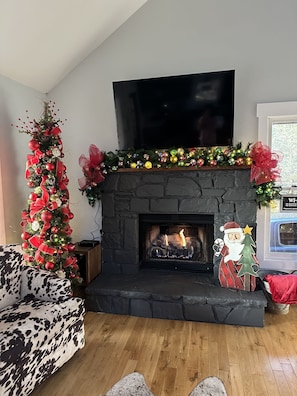 Cozy living room with a fireplace, flat-screen TV, and a cow-print sofa.