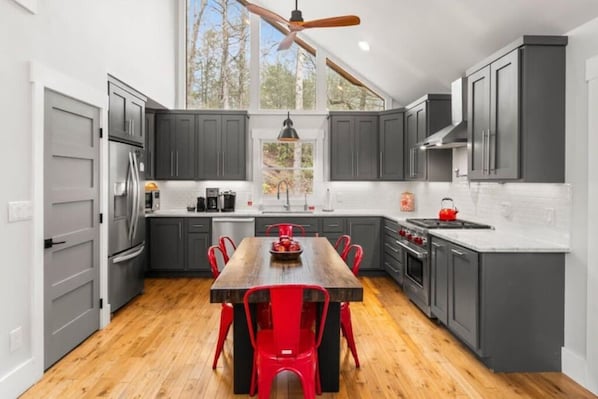 Enjoy cooking in this well-equipped kitchen with a central island, stainless steel appliances, and a large window offering a view of the surrounding trees.