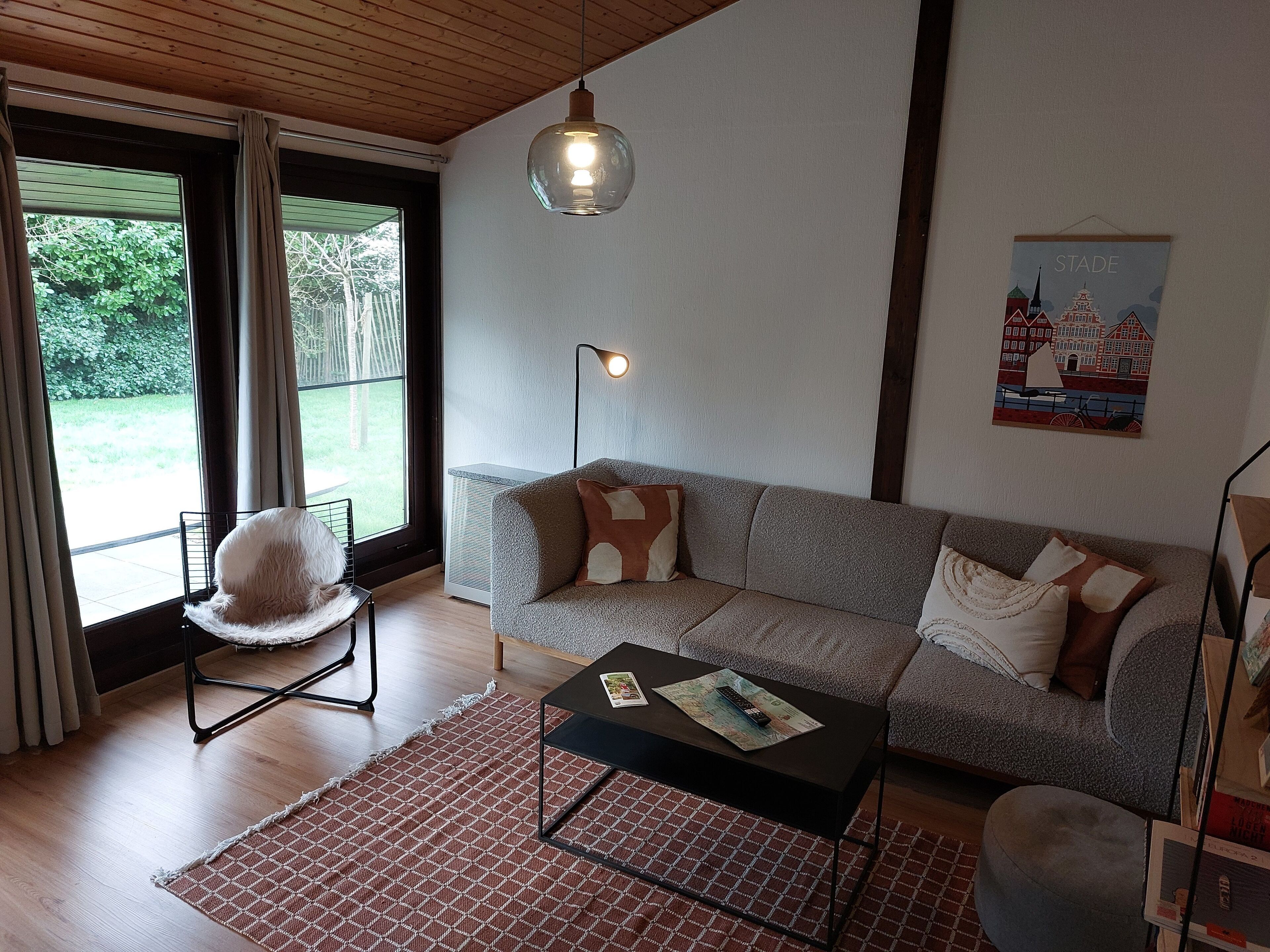 Ein modernes Wohnzimmer mit einem grauen Sofa, einem schwarzen Couchtisch und einer Pendelleuchte.