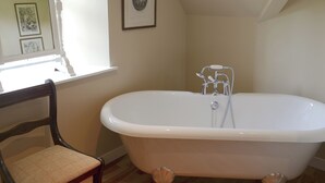 A bathroom with a freestanding bathtub, a wooden chair, and a framed picture on the wall. - Tressady Coach House (Rogart, near Dornoch)