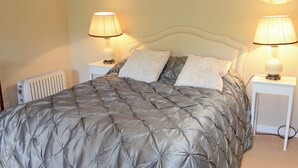 A neatly made bed with a grey quilt, two bedside lamps, and a white radiator. - Tressady Coach House (Rogart, near Dornoch)