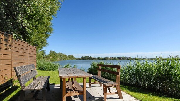 Una mesa de picnic de madera y bancos junto a un lago.