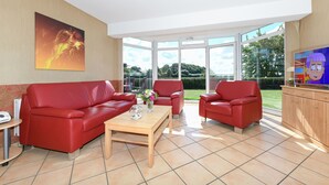 Una sala moderna con un sofá rojo, una mesa de centro de madera y un televisor.