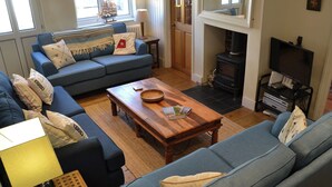 Una sala de estar acogedora con un sofá azul, una mesa de centro de madera y una chimenea.