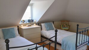 Un dormitorio con dos camas, una mesita de noche, un aparador y una ventana con persianas.