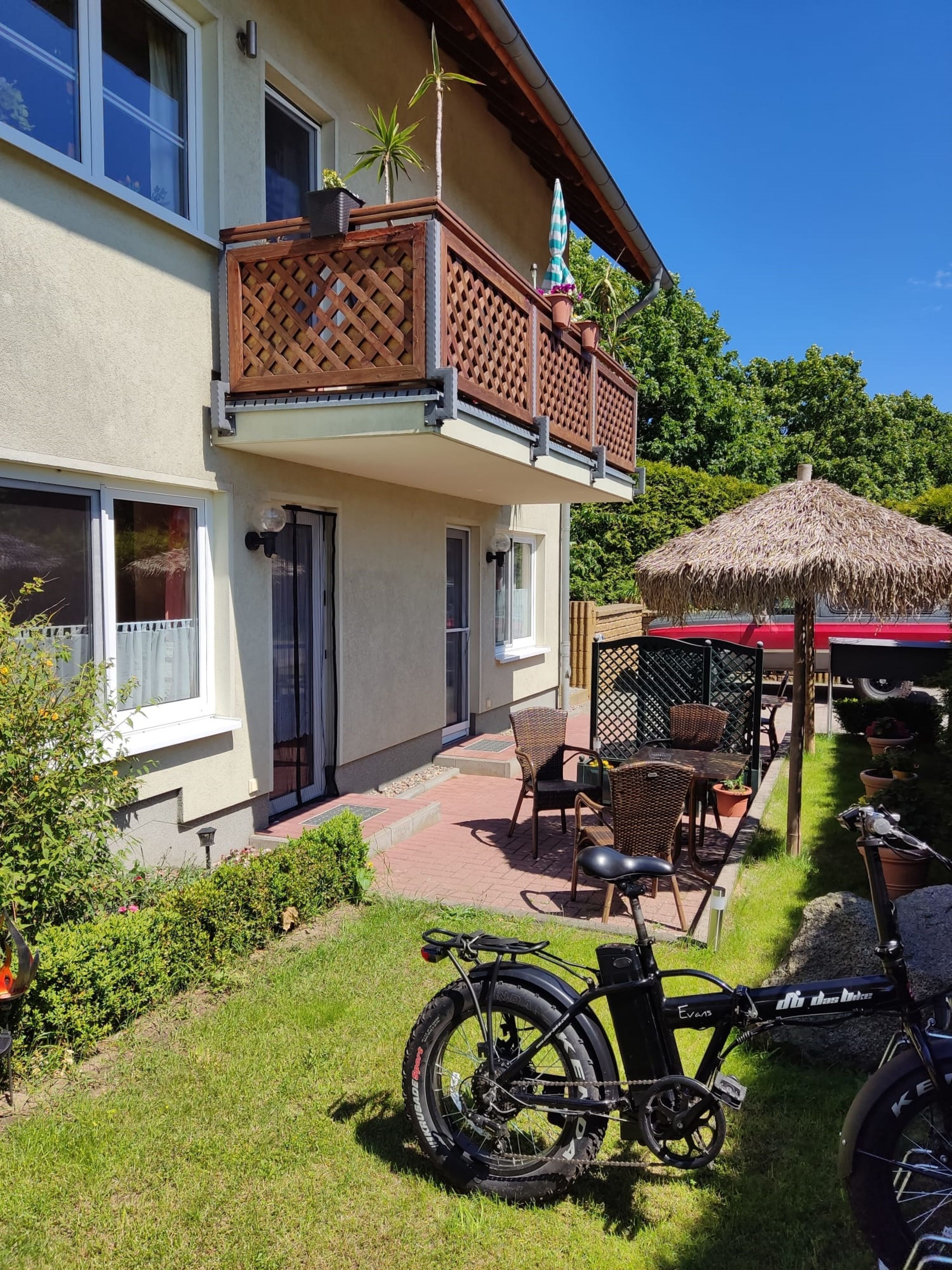 En toetagers bygning med balkon, udendørs siddeområde og en cykel i gården.