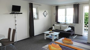 Una habitación de hotel con cama, sofá, televisión, escritorio y una silla.