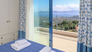 A bedroom with a bed, a view of the sea, and a balcony.