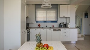 A modern kitchen with white cabinets, a stainless steel sink, and a fruit bowl on the counter.