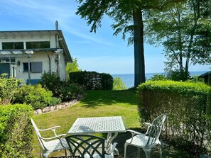 A modern house with a view of the sea, a grassy garden, and a table with chairs. - Apartment III: Ground floor South & Sea - Villa Achterkerke (Heringsdorf)