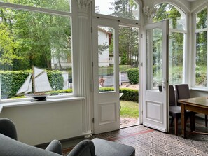 Ein Wintergarten mit einem Modell eines Segelbootes, einem Essbereich mit Stühlen und einem gemusterten Boden.