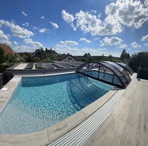A swimming pool with a clear blue water surface, surrounded by a wooden deck.
