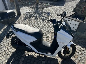 Una patineta blanca y negra estacionada en una calle empedrada.
