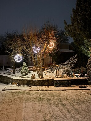 A snow-covered outdoor area with a tree and decorative lights.