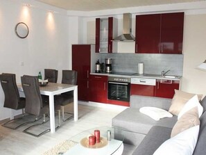 Un espacio habitable compacto con comedor, kitchenette y sofá.