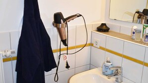 Une salle de bain équipée d’un lavabo, d’un miroir et d’un sèche-cheveux.