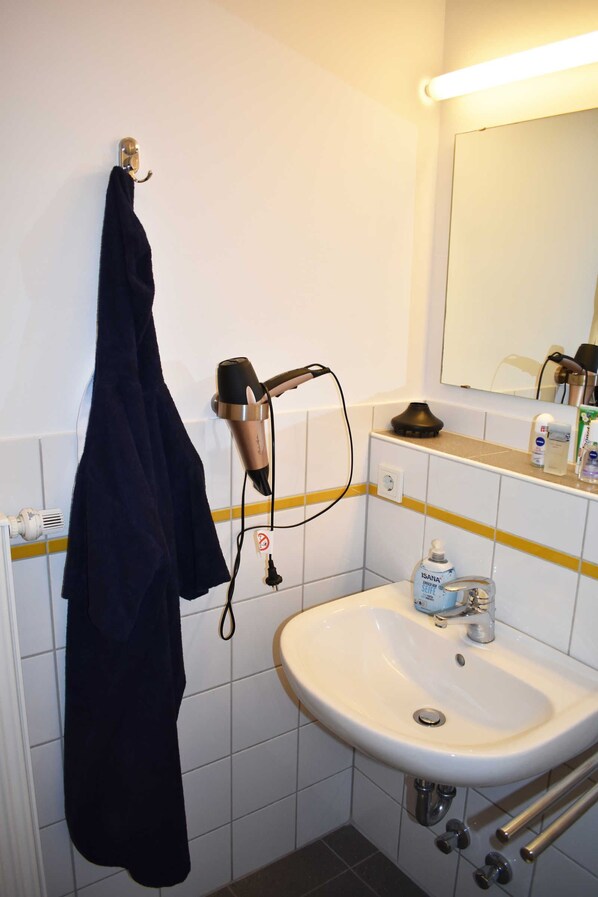 A bathroom with a sink, mirror, and hairdryer.