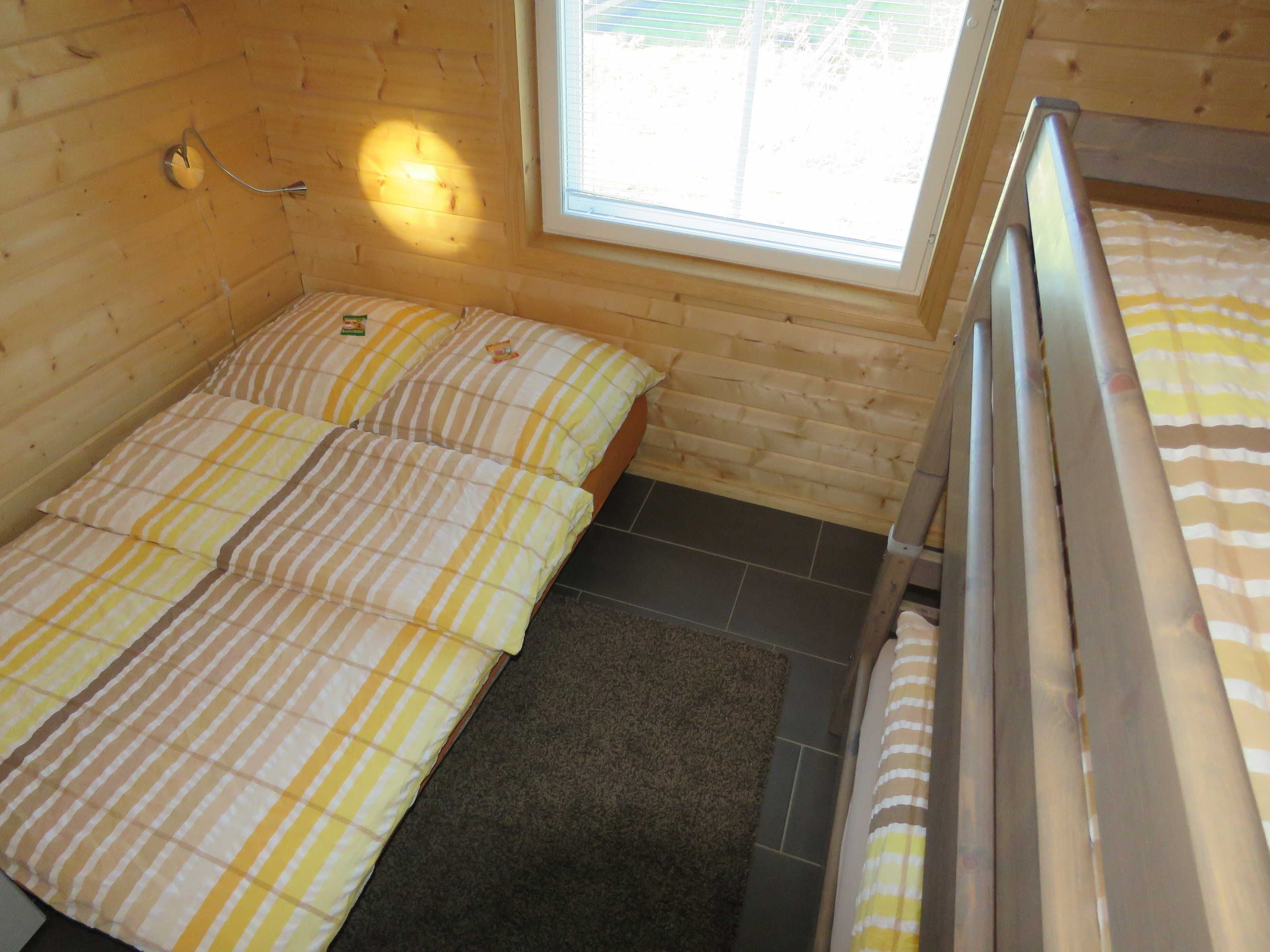 Une petite chambre confortable, avec deux lits simples, une fenêtre et un intérieur en bois.
