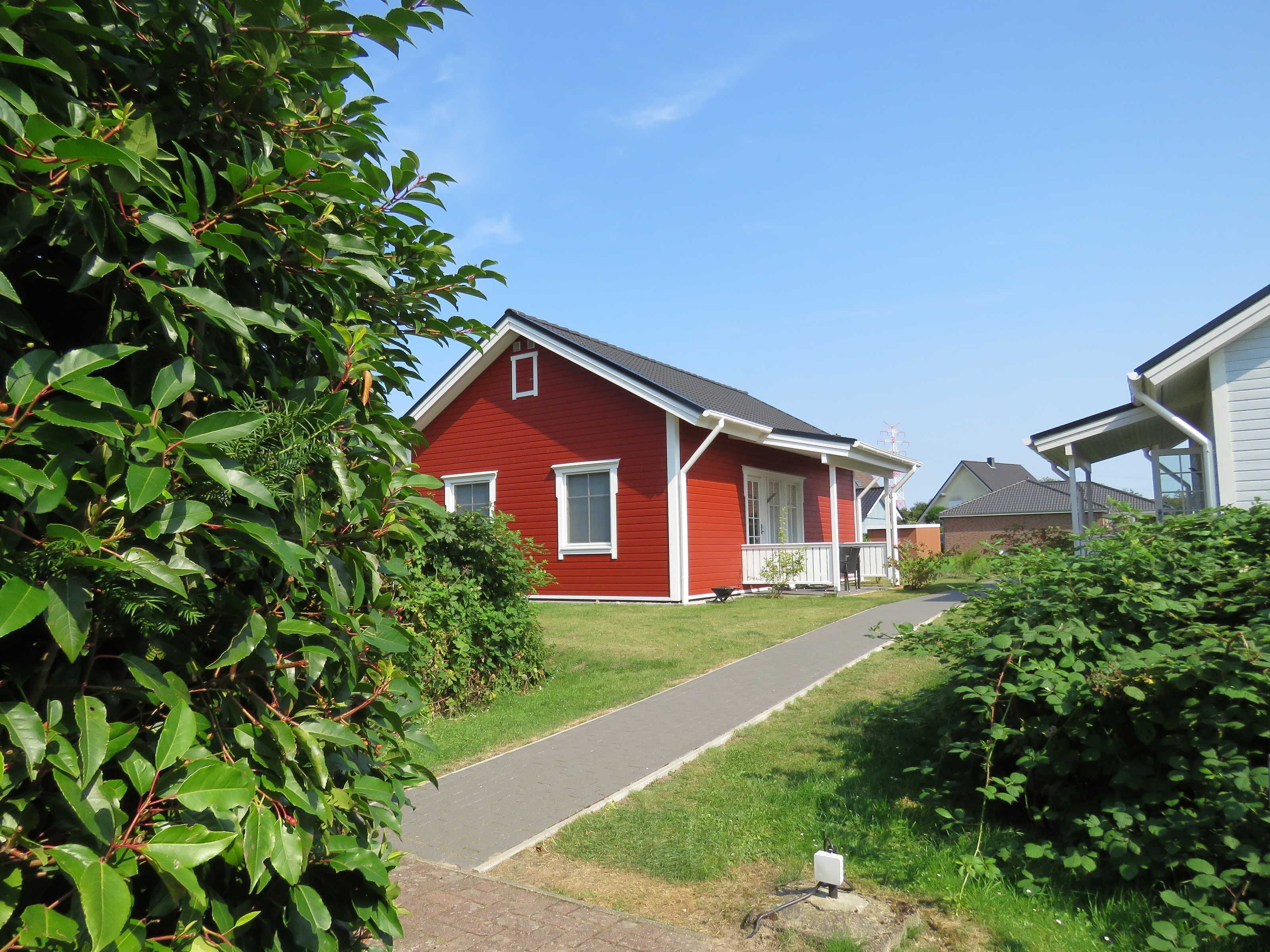 Ein rotes Haus mit weißer Veranda und blauem Himmel.