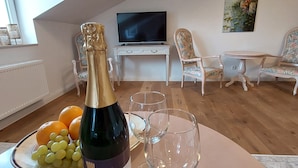 Een woonkamer met een fles wijn, glazen, sinaasappels en druiven op een tafel.