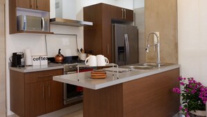 Eine moderne Küche mit Holzschränken, einem Edelstahlkühlschrank, einer Mikrowelle und einer Kaffeestation.