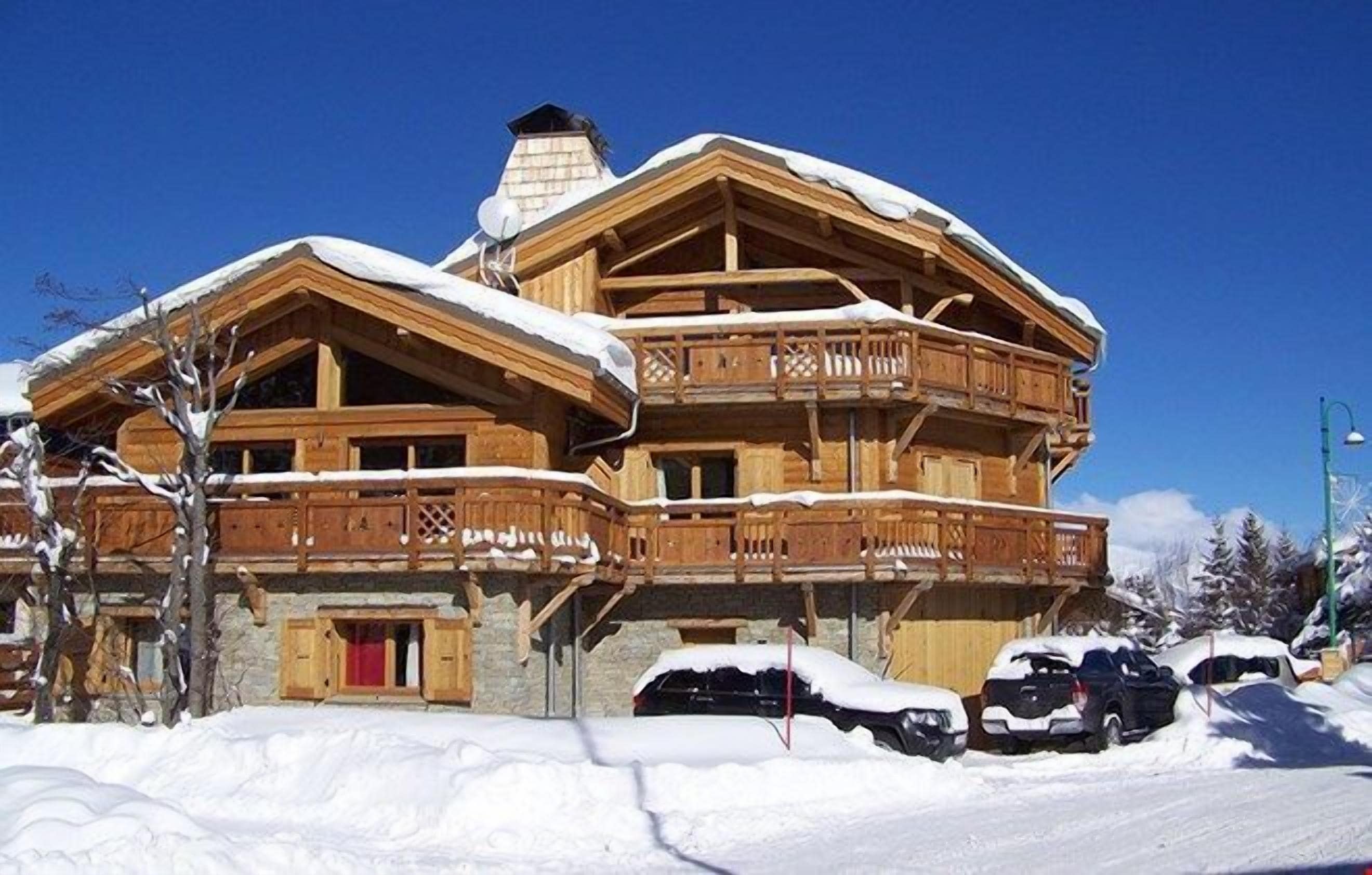 A multi-story wooden chalet with balconies, surrounded by snow.