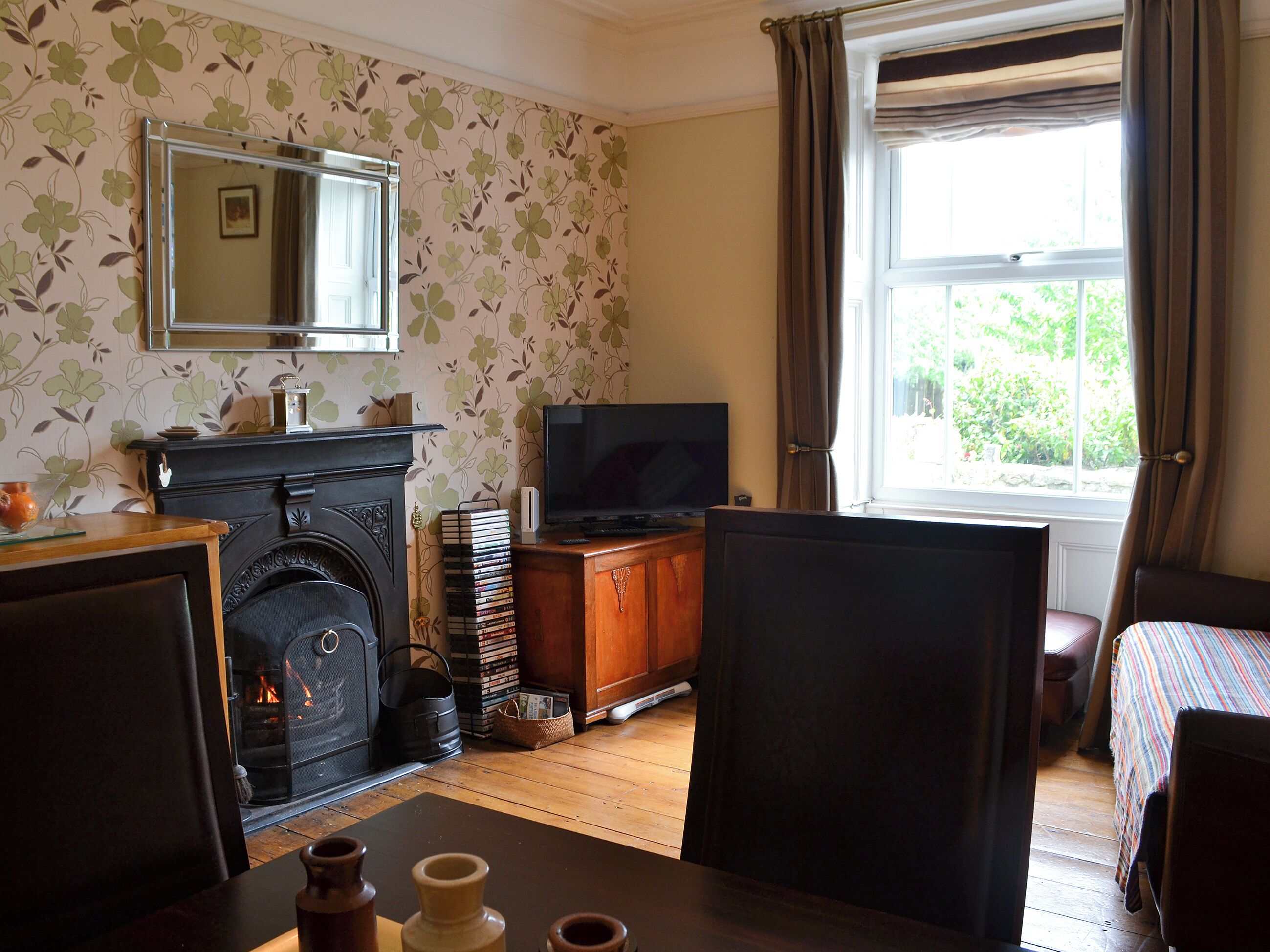 A room with a fireplace, a television, a window with curtains, and a bed.