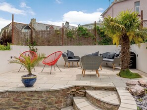 Ein Patio mit Gartenmöbeln, einer Steinmauer und einem Blumentopf.