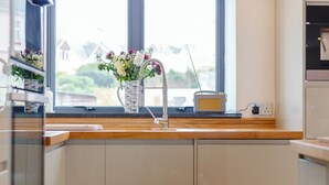 A kitchen with a wooden countertop, a sink, a vase with flowers, and a radio.