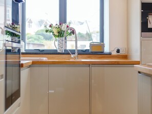 Une cuisine avec un plan de travail en bois, un évier, un vase de fleurs et une radio.