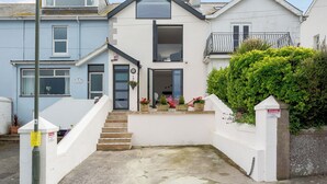 A two-story residential building with a white facade, a balcony, and a small front garden. - 3 bedroom accommodation in Brixham (Brixham)