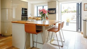 A modern kitchen with a central island, bar stools, and a view of the outside.