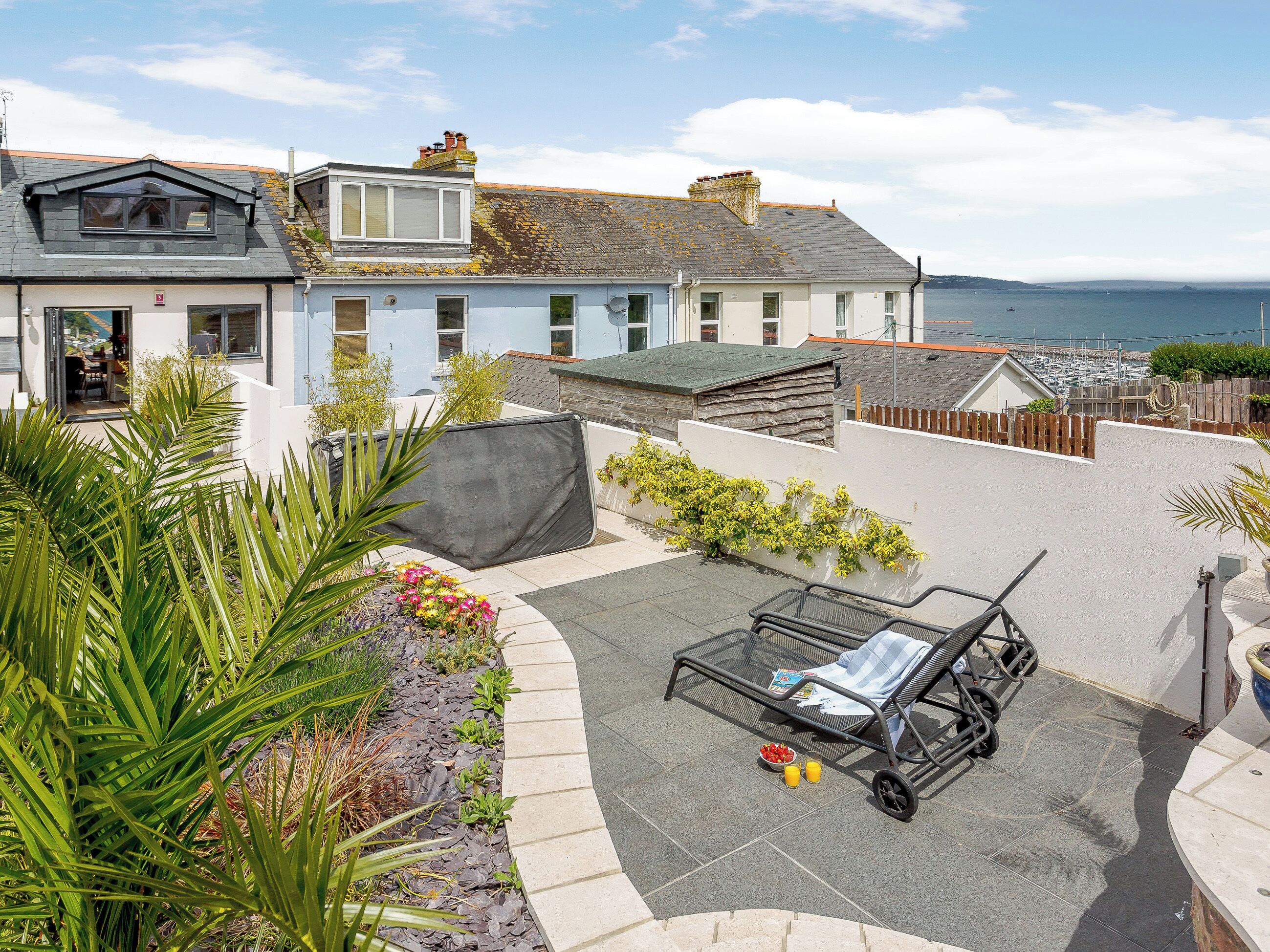 A residential property with a patio area, a covered seating area, and a view of the sea.