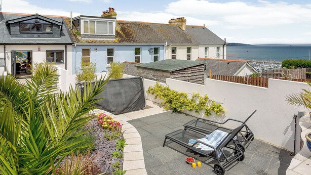 A residential property with a patio area, a covered seating area, and a view of the sea.