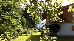 Un jardin avec une maison en bois, une terrasse couverte et une pelouse.
