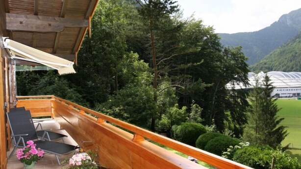 A wooden balcony with a view of a mountainous landscape and a greenhouse. - Ferienwohnung für 2 Personen mit großem Balkon, 79 m² (Inzell)