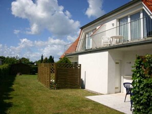 A two-story house with a balcony, a fenced backyard, and a clear sky.