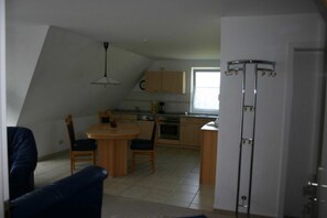 A compact kitchen with a dining area, a ceiling fan, and a window.