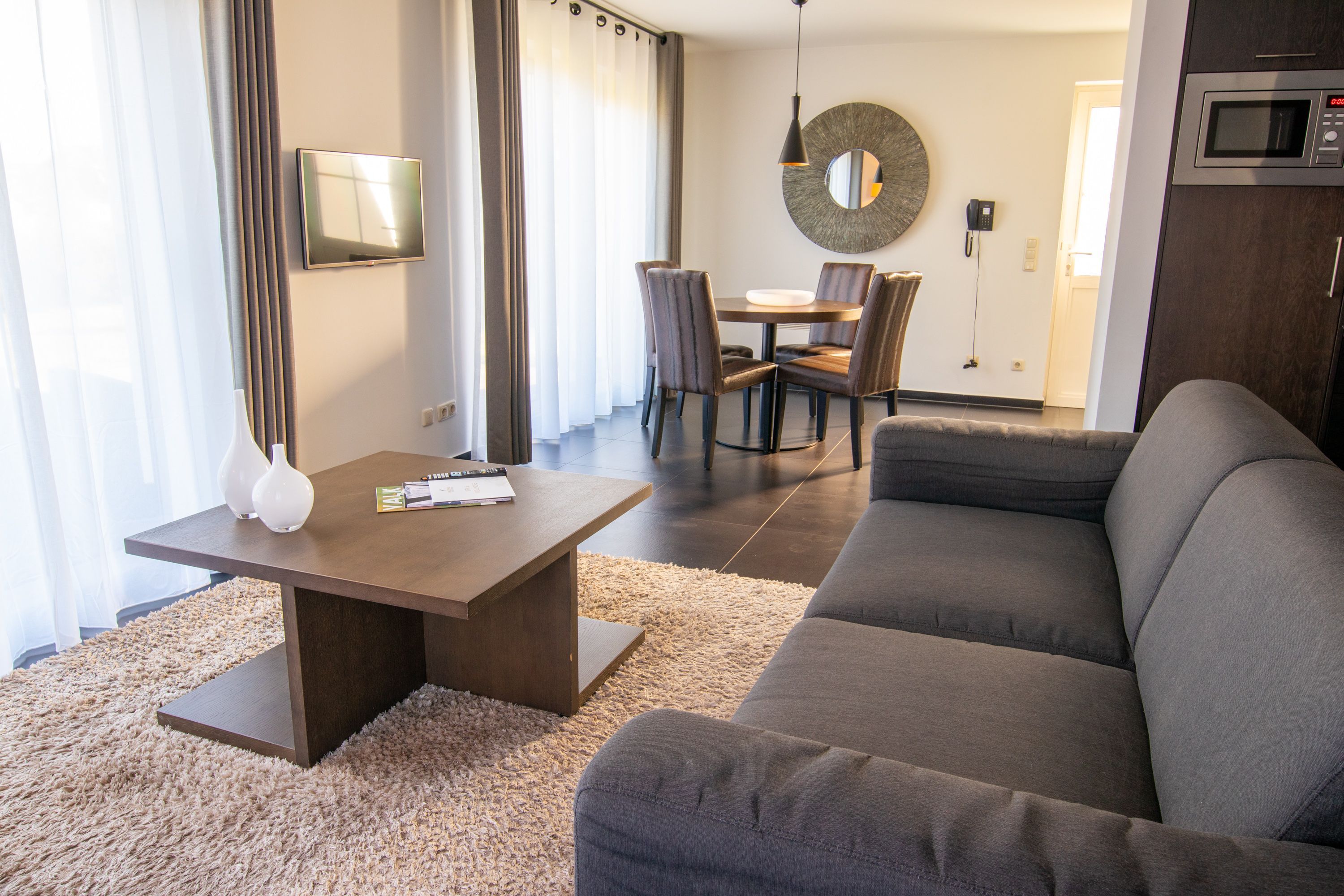 Un salon moderne comprenant un canapé, une table basse et un coin repas avec des chaises et une table.