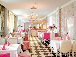 A dining area with tables and chairs, a checkered floor, and floral wallpaper. - Holiday home Type V - Van der Valk Resort Linstow (Dobbin-Linstow)