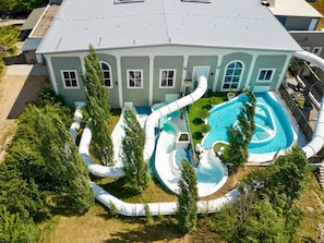 A large house with a swimming pool, multiple slides, and a fenced yard. - Holiday home Type V - Van der Valk Resort Linstow (Dobbin-Linstow)