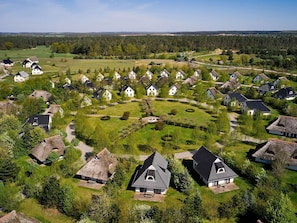 En landsby med traditionelle huse, et grønt område i midten og en bygning med stråtækt tag.