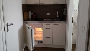 Une cuisine de taille réduite avec des meubles blancs, un four encastré et un évier.