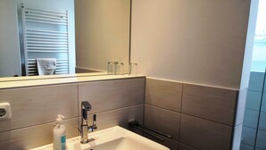 Une salle de bain avec un lavabo blanc, un miroir et un porte-serviettes.