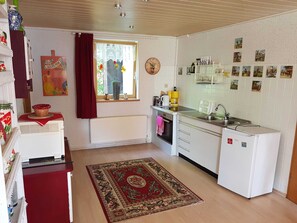 A compact kitchen with a radiator, a small refrigerator, a sink, and a window with a view.