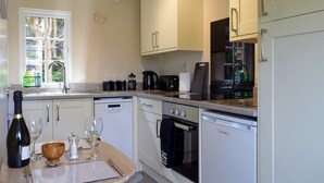 Une cuisine moderne avec des meubles blancs, un lave-vaisselle, un four et un coin repas avec une table mise pour deux personnes.