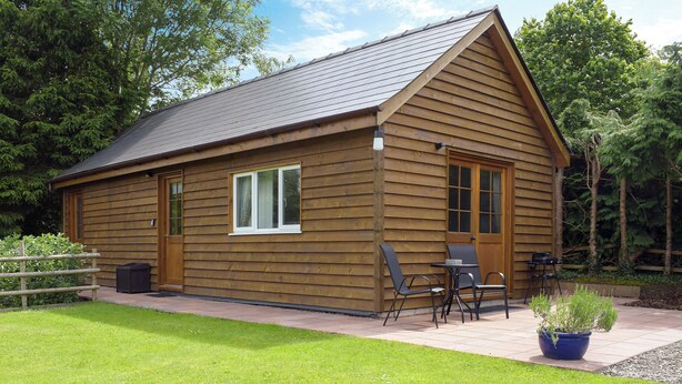 Une cabane en bois avec une terrasse, une petite table et des chaises.
