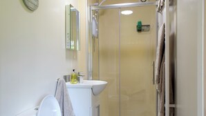 Une salle de bain moderne équipée de toilettes, d’un lavabo et d’une douche à parois de verre.